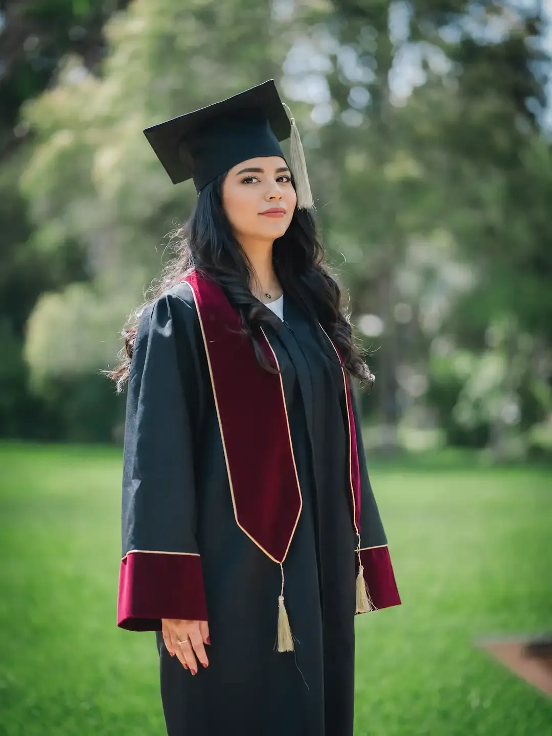 Toge de graduation avec écharpe et parements bordeaux, portée avec le mortier assorti
