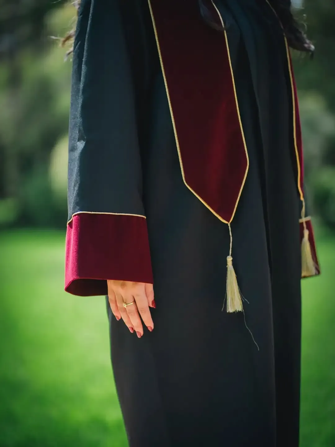 Détail d'une écharpe de graduation bordeaux avec liseré et gland dorés